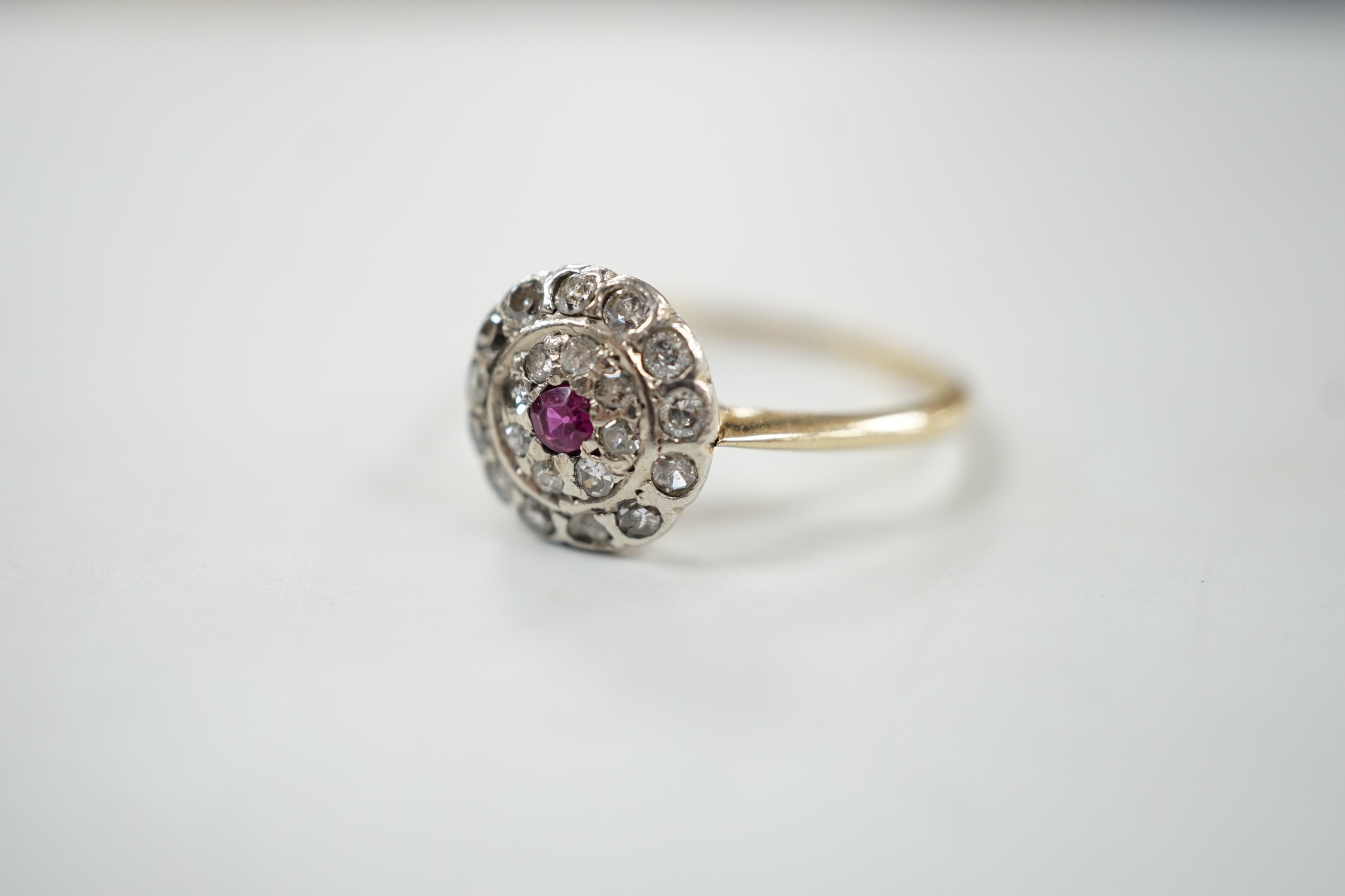 An early to mid 20th century, yellow metal ruby and diamond set target cluster ring, size P, gross weight 2.8 grams.